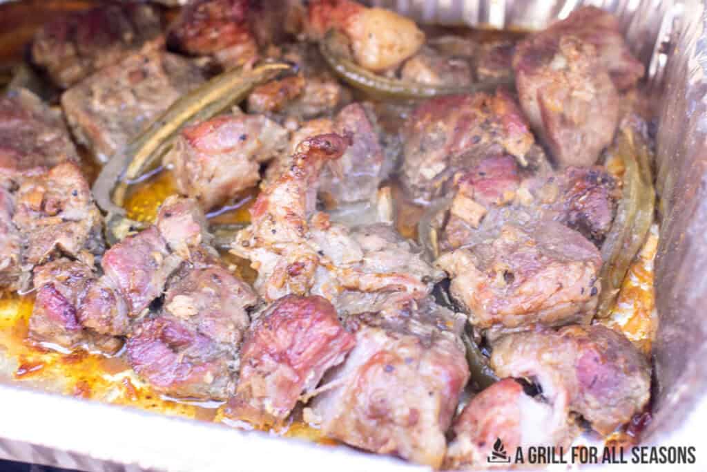 meat in foil tray with a few pieces of jalapeno