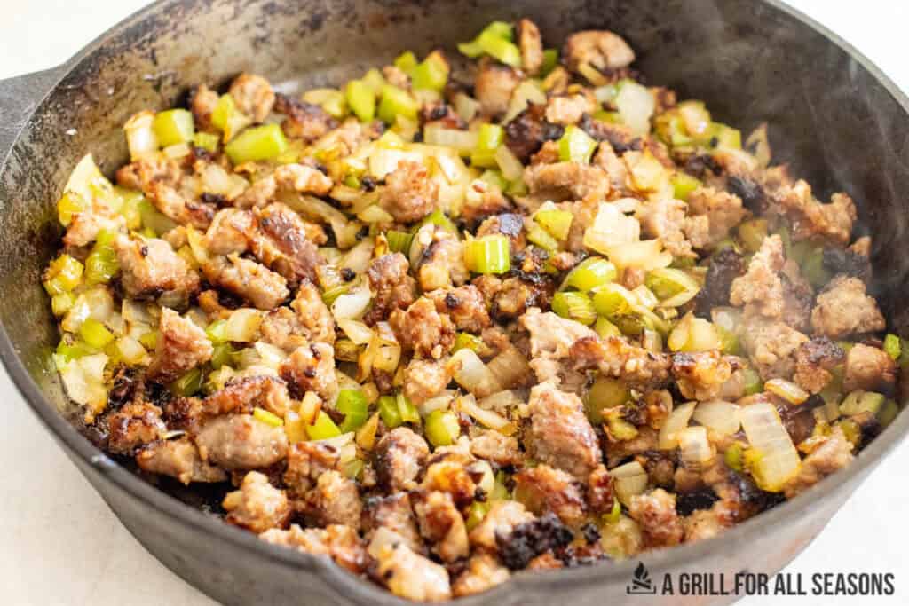 cooked sausage, onions, and celery in cast iron pan